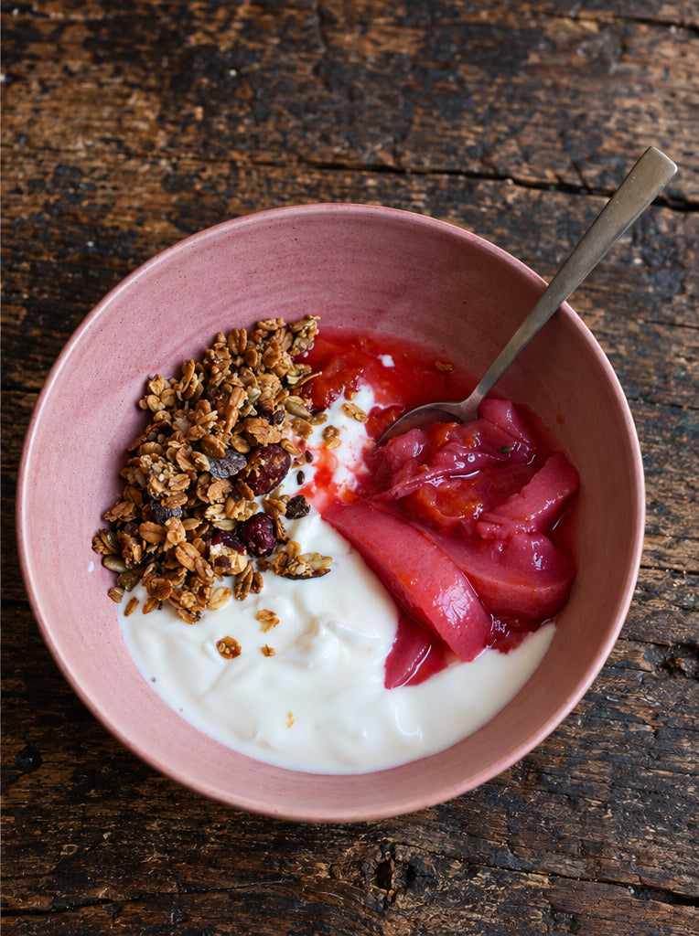 Bol rose de granola, yaourt et fruits pochés